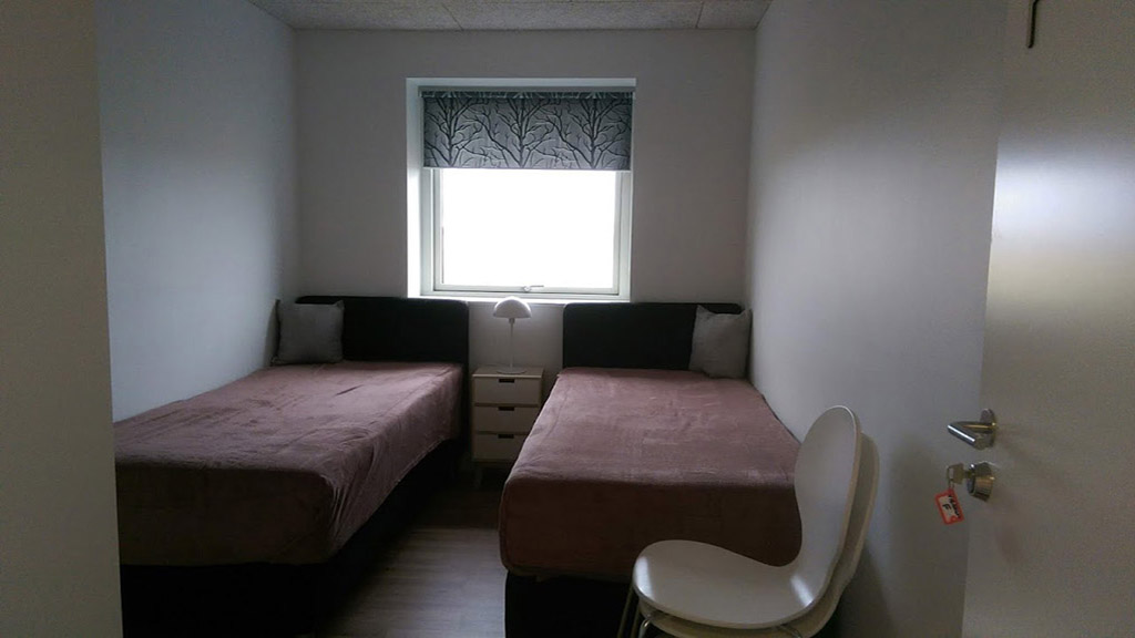 Two beds and a chair in room E in Common House Kirkebakken