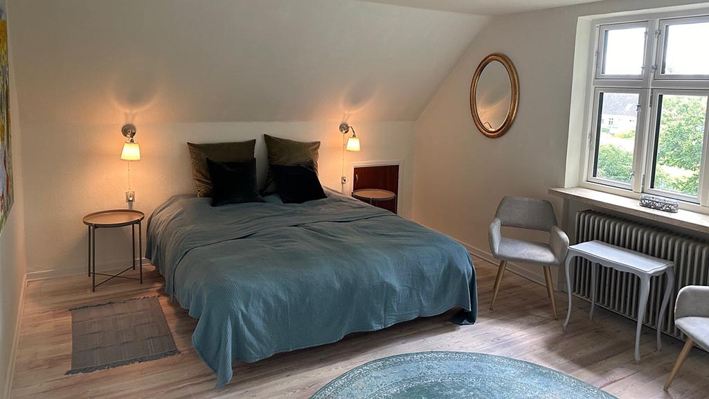Bedroom with double bed and two chairs at Æbelø B&B