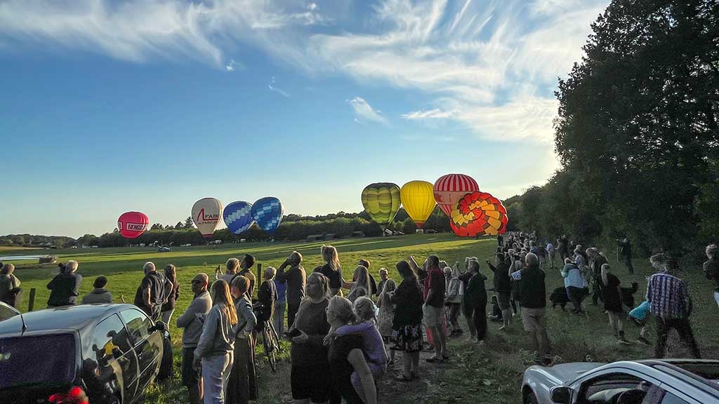 Eine Gruppe von Menschen, die die Ballons auf dem Feld für den Dream Balloon Cup beobachten