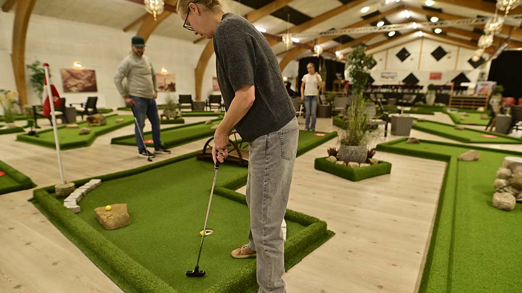 Several people are playing mini golf indoors at the Støberiet cultural centre.