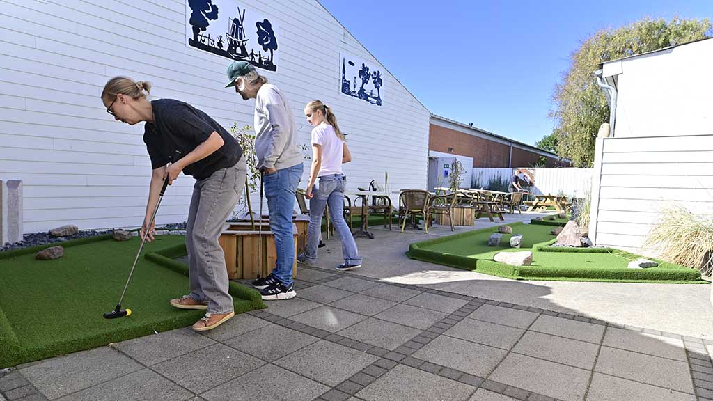 Family playing mini golf outdoors in Bogense