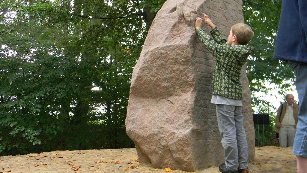 A boy points to the runes on the Glavendrup stone