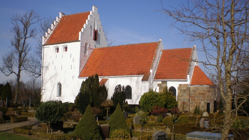 Den hvidtkalkede Melby Kirke og kirkegården en skyfri vinterdag