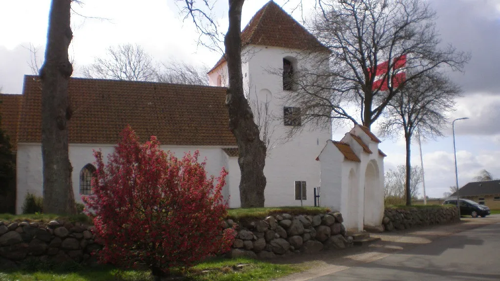 Ejlby Church on a gray day, while the Dannebrog flag flies