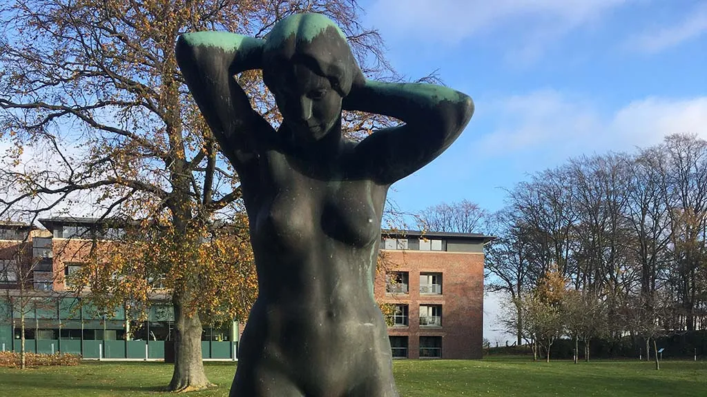 ed Nyborg Strand findes en bronzeskulptur af en nøgen kvinde, der er hensunket i tanker og i færd med at sætte sit hår.