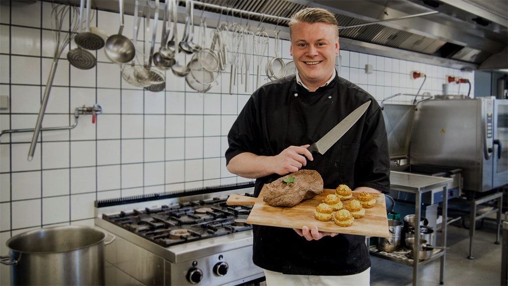 Kok præsentere mad på skærebræt i køkkenet på Næsbjerghus