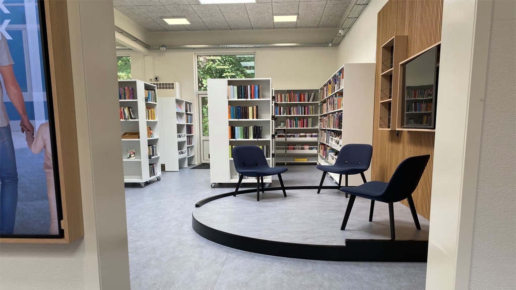 Agerbæk Bibliotek set indefra med bogreoler og tre blå stole
