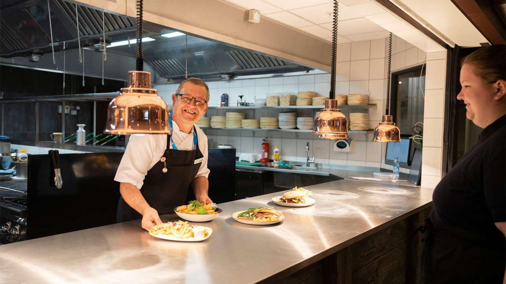 A chef serves food directly from the kitchen