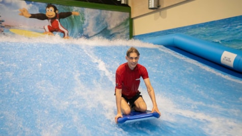 Dreng som surfer på en indendørs surf bane
