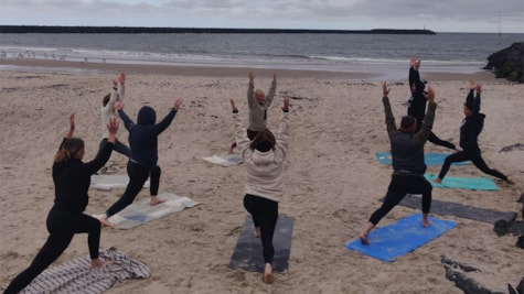 En gruppe som laver yoga på stranden