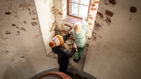 Dreng og mor kigger ud gennem de små vinduer i Lyngvig Fyr