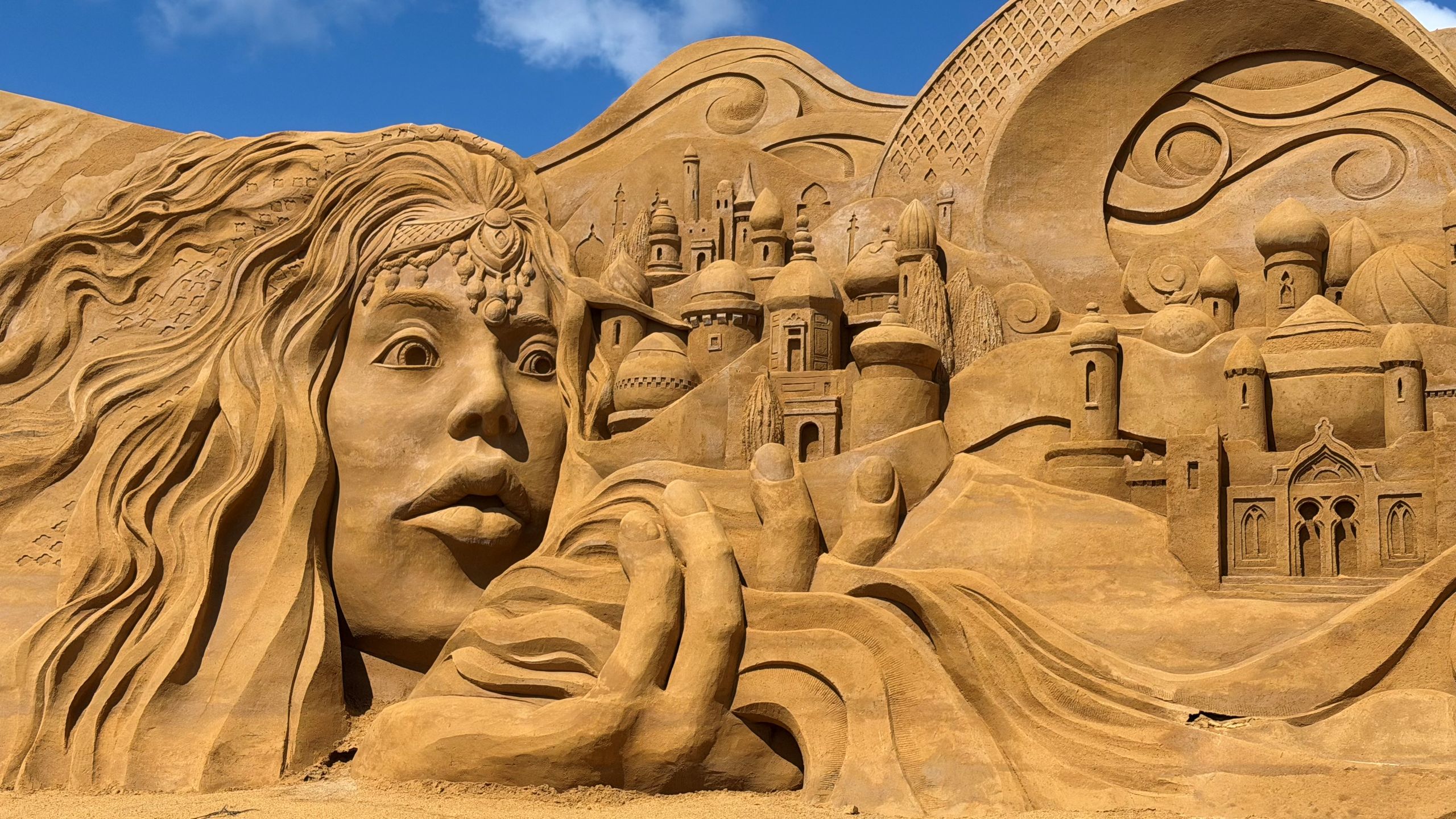 Sandskulptur af eventyrkvinde foran orientalsk by
