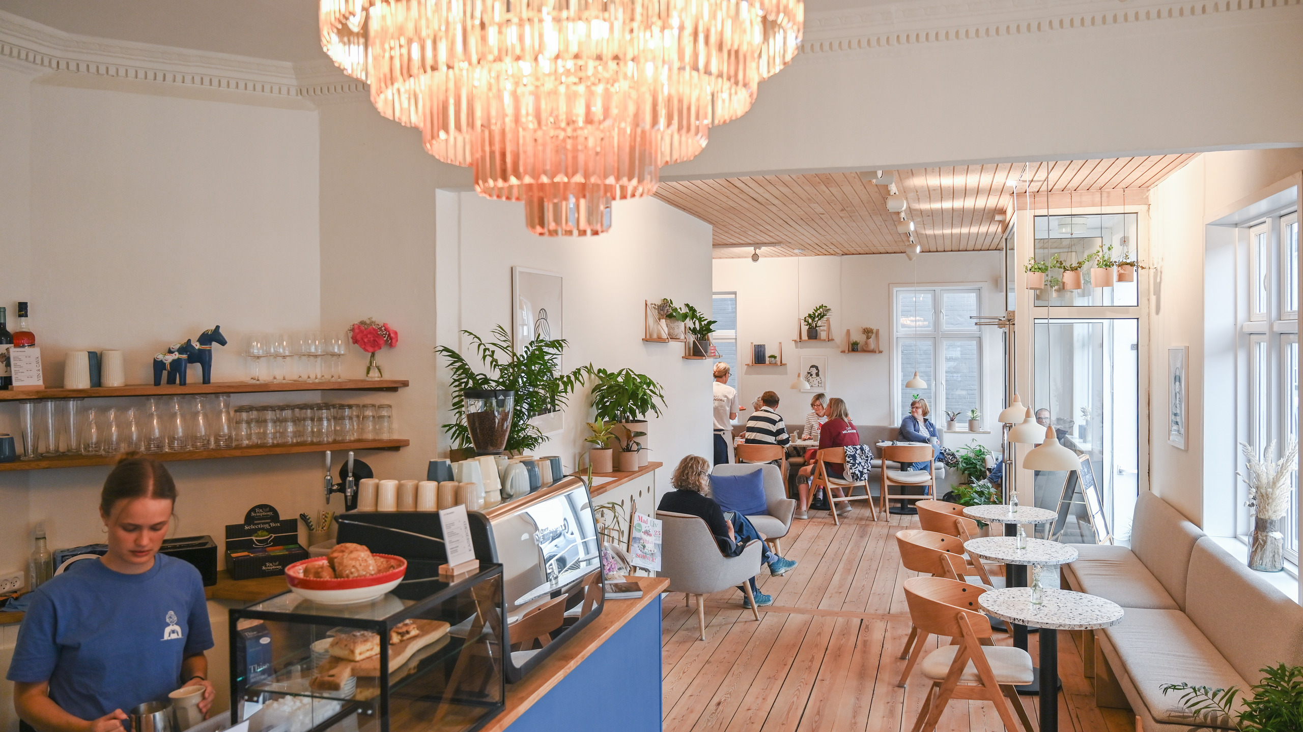 A cosy venue with a café bar, tables, chairs and sofa benches.