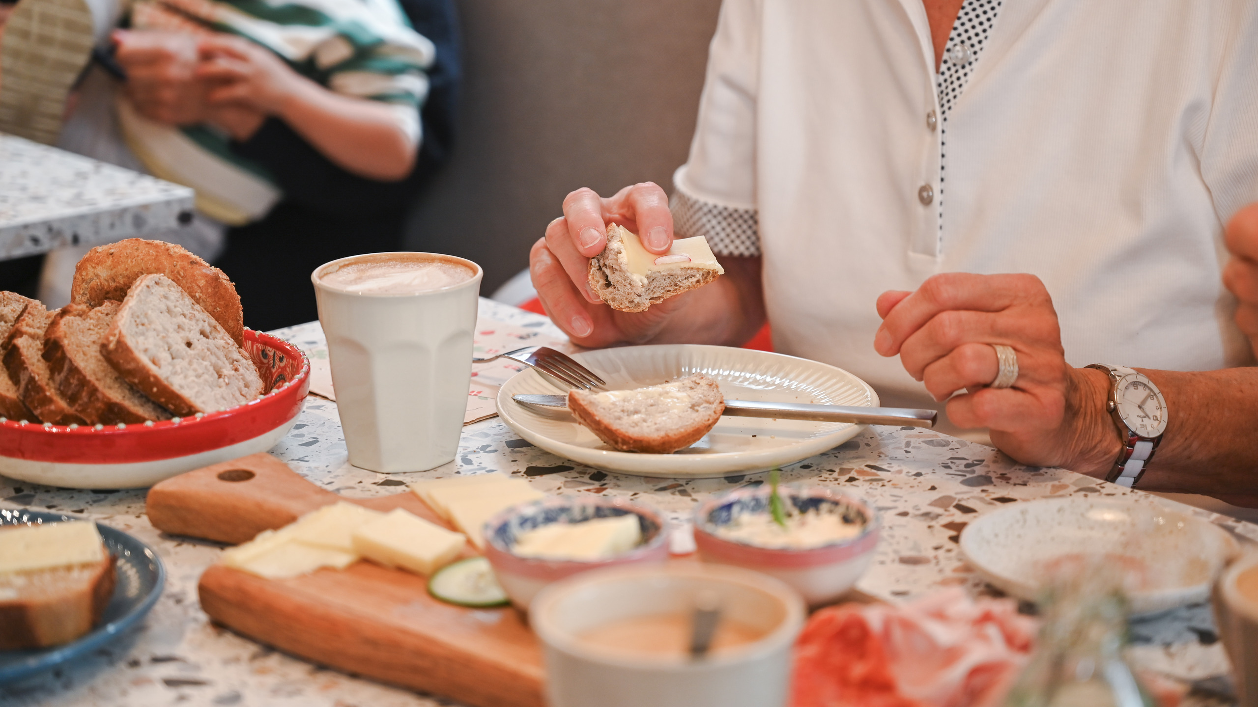 A table laid with a delicious breakfast and people eating in a relaxed atmosphere.