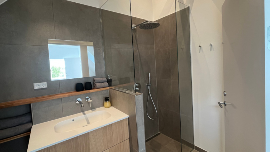 Et lille badeværelse med moderne indretning, udstyret med brusebad, håndvask og toilet.