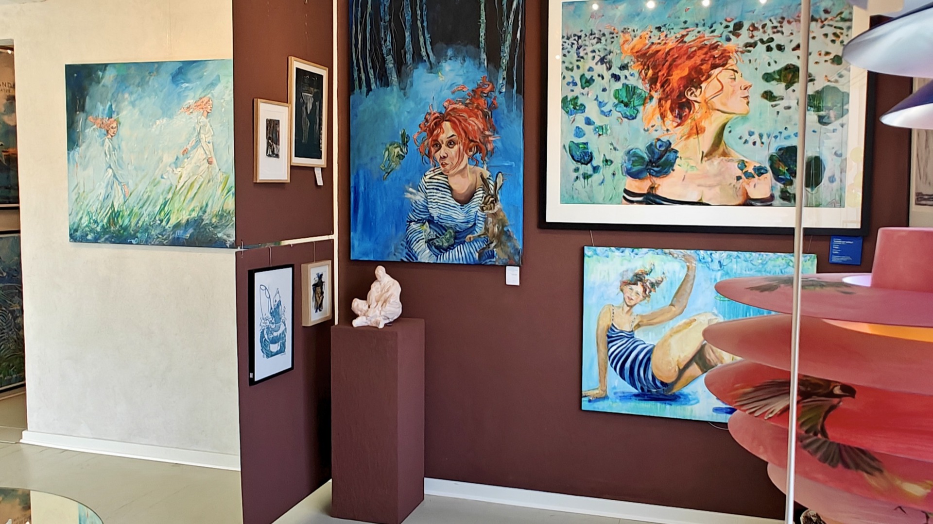 Farverige malerier og kunstværker udstillet i galleri.