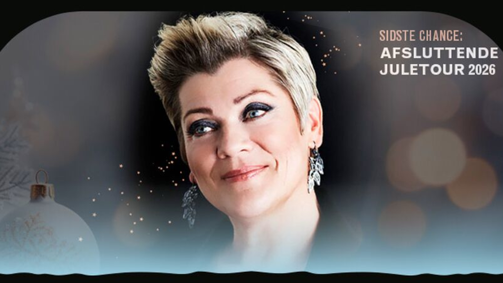 Billedet viser Ann Mette Elten, der smiler foran en julestemningsfuld baggrund.