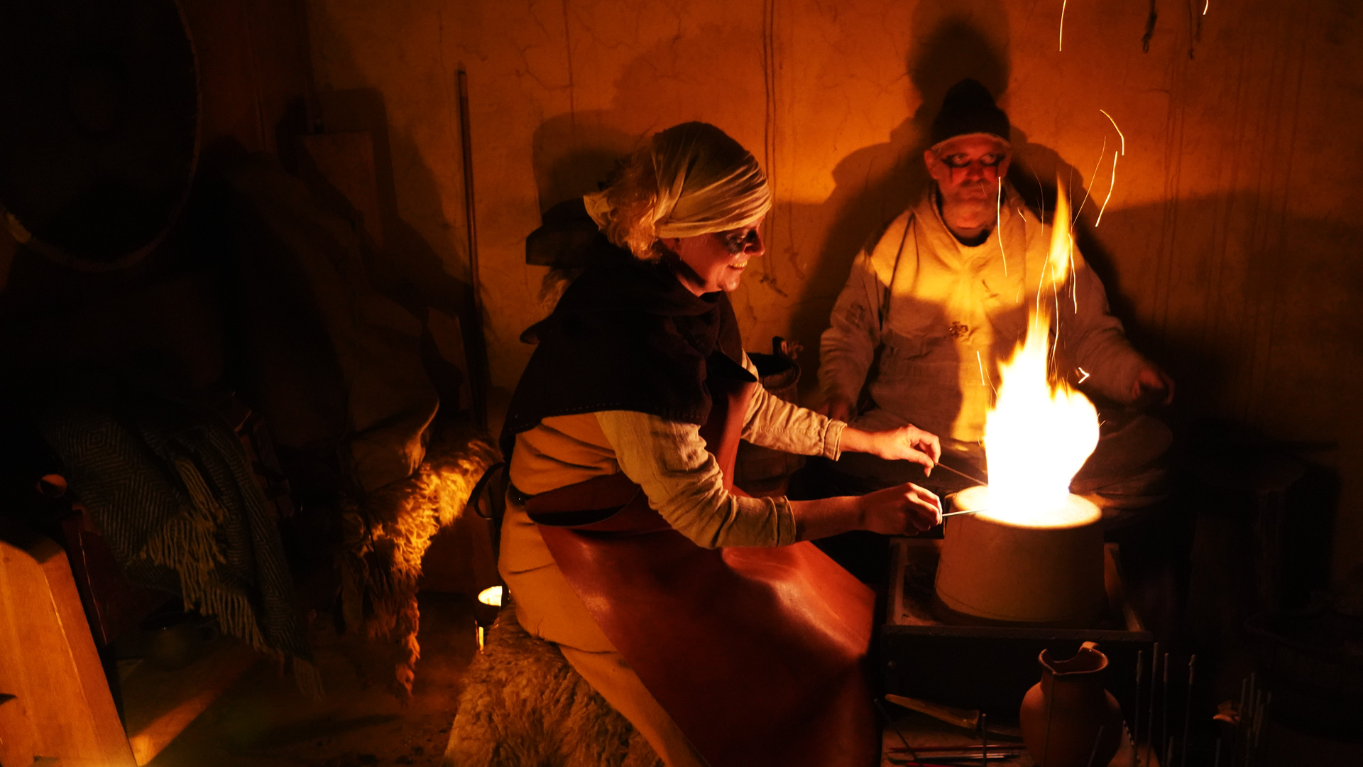 Wikinger an einer lodernden Feuerstelle in einem Wikingerhaus