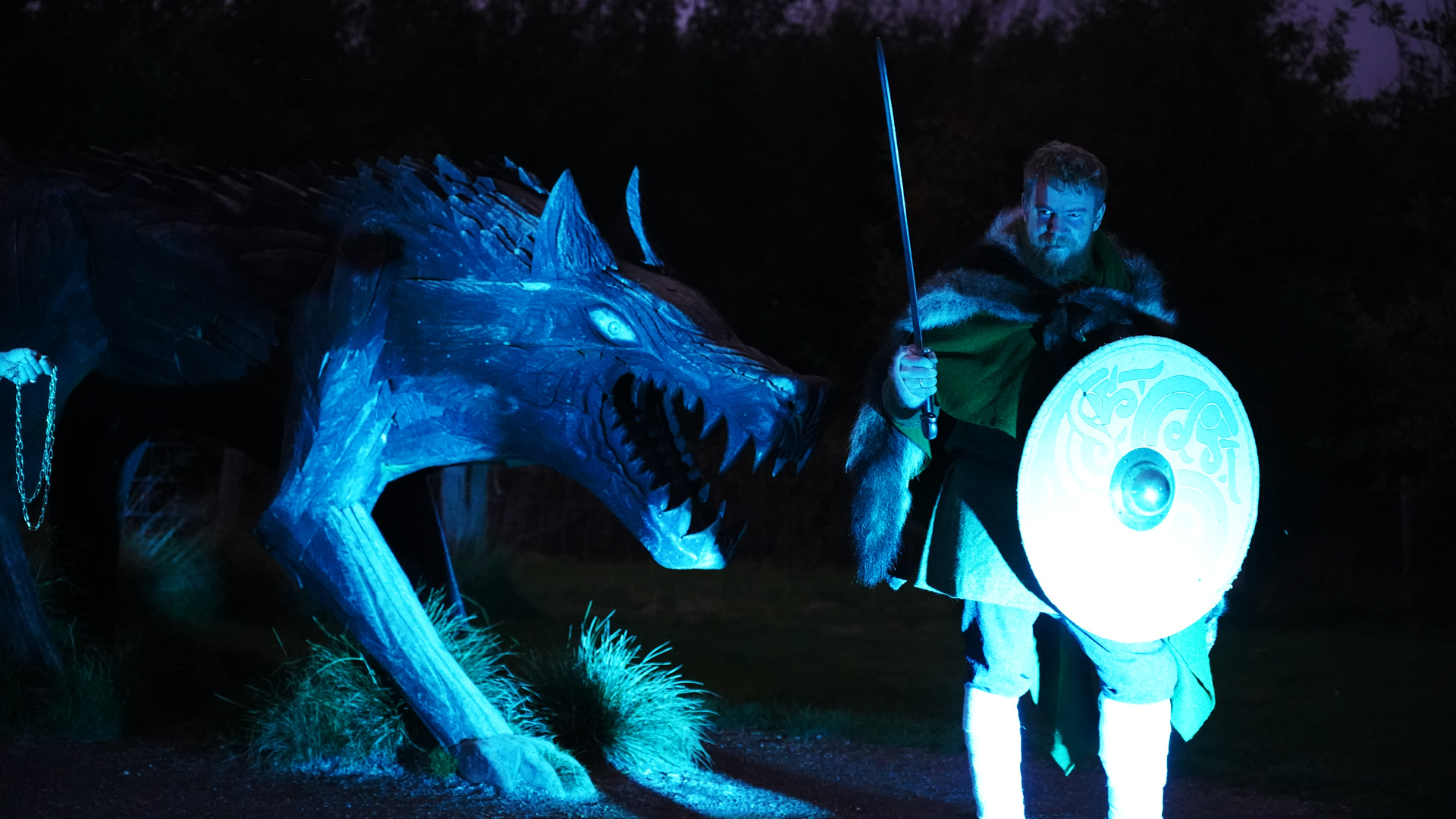 Wikinger mit Schwert und Schild neben einem großen Wolfskopf