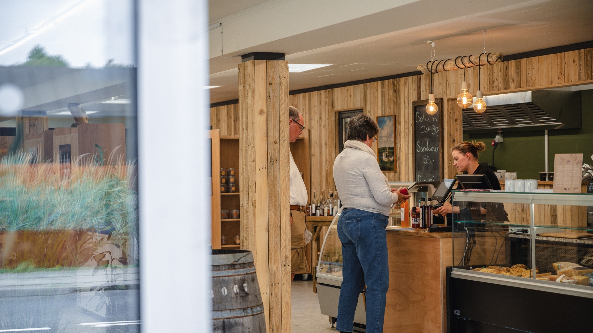 Kunden werden an der Theke eines Cafés mit lokalen Produkten bedient.