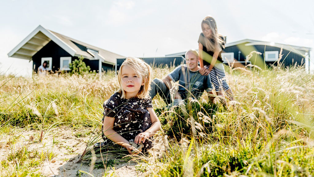 Feline Holidays - Mann und Kinder genießen die Natur vor dem Ferienhaus