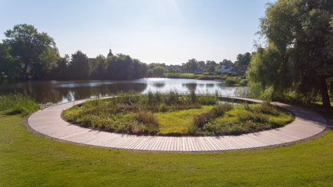 Uendelighedsbroen i Nordborg Søpark med glimt af Nordborg Slot på øen Als