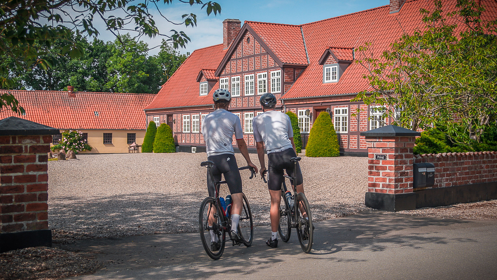 Two cyclists in front of a historic half-timbered farmhouse on Langeland