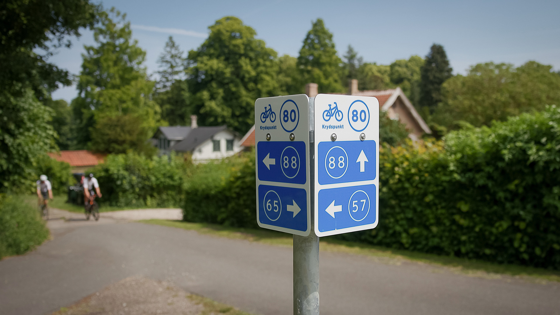 Beschilderung der Knotenpunkte im Radwegenetz mit Radfahrern im Hintergrund bei Tranekær