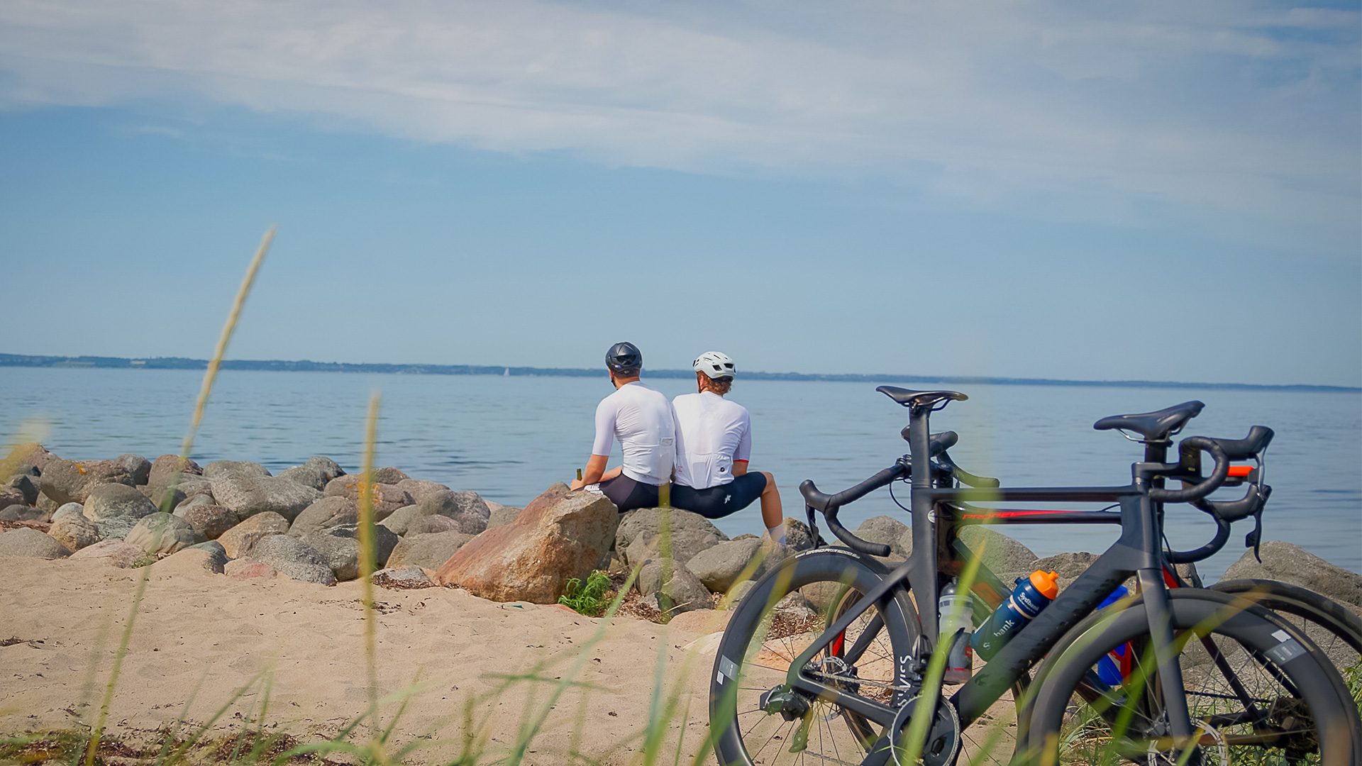 Zwei Radfahrer machen Pause am Strand mit Blick aufs Meer auf Langeland