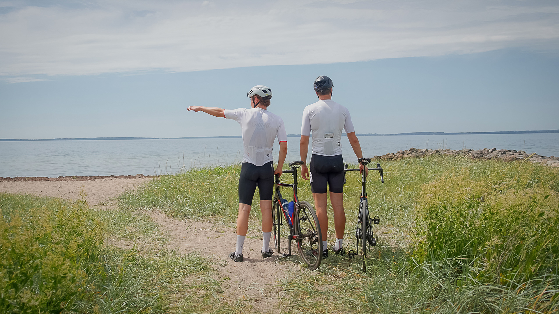 Zwei Radfahrer mit ihren Fahrrädern an der Küste mit Blick aufs Meer auf Langeland