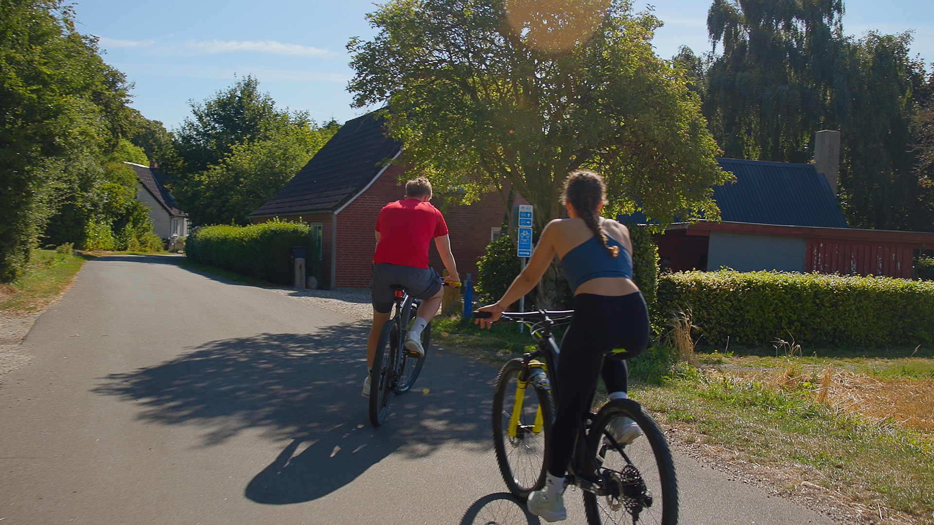 Two cyclists following the cycle route through a village on northern Langeland