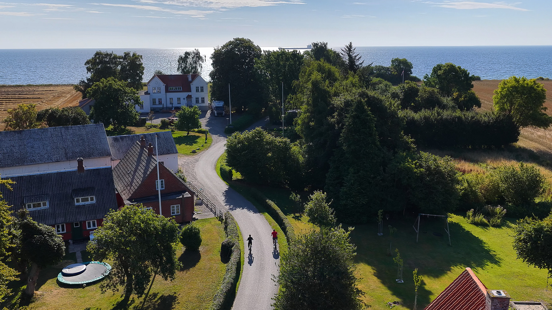 Two cyclists riding through a village on northern Langeland with the sea in the background