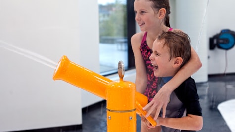 Dreng og pige griner og har det sjovt med at sprøjte med vand i SlotssøBadets SprayPark