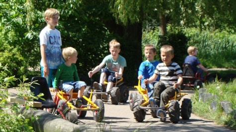 6 Kinder sind damit beschäftigt, Mooncars auf den Gleisen im Madsby Play Park zu fahren.