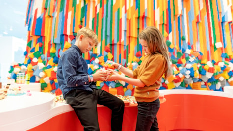 2 børn bygger med LEGO® klodser foran LEGO vandfaldet i LEGO House
