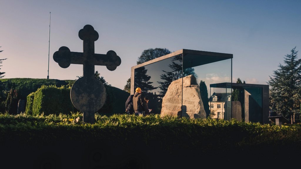  Tag på vandretur i Jelling og se Jellingstenene og korset side om side, der markerer Danmarks overgang til kristendom, rejst af Harald Blåtand som symbol på danernes dåb og kristendommens indførelse i vikingetiden