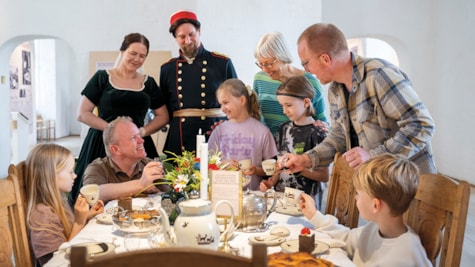 En børnefamilien sidder ved et smukt dækket bord og leger, at de er kongelige i en dag på Koldinghus.