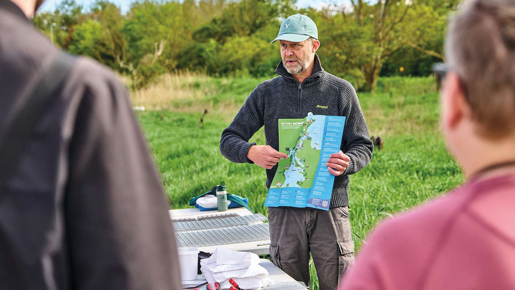 En flok gæster i Naturpark Lillebælt er klar til at bygge fiskebørnehaver. En guide er ved at forklare, hvor fiskebørnehaverne skal sættes ud i Lillebælt.