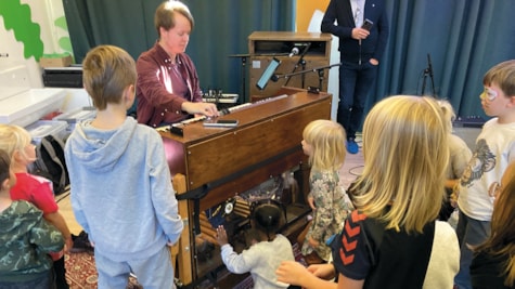 Børn samles omkring et mekanisk instrument på Kulturhuset Nicolai for Børn i Kolding, mens en musiker demonstrerer, hvordan det fungerer.