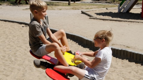 To drenge leger på en vippe i sandkassen i Legeparken i Kolding.