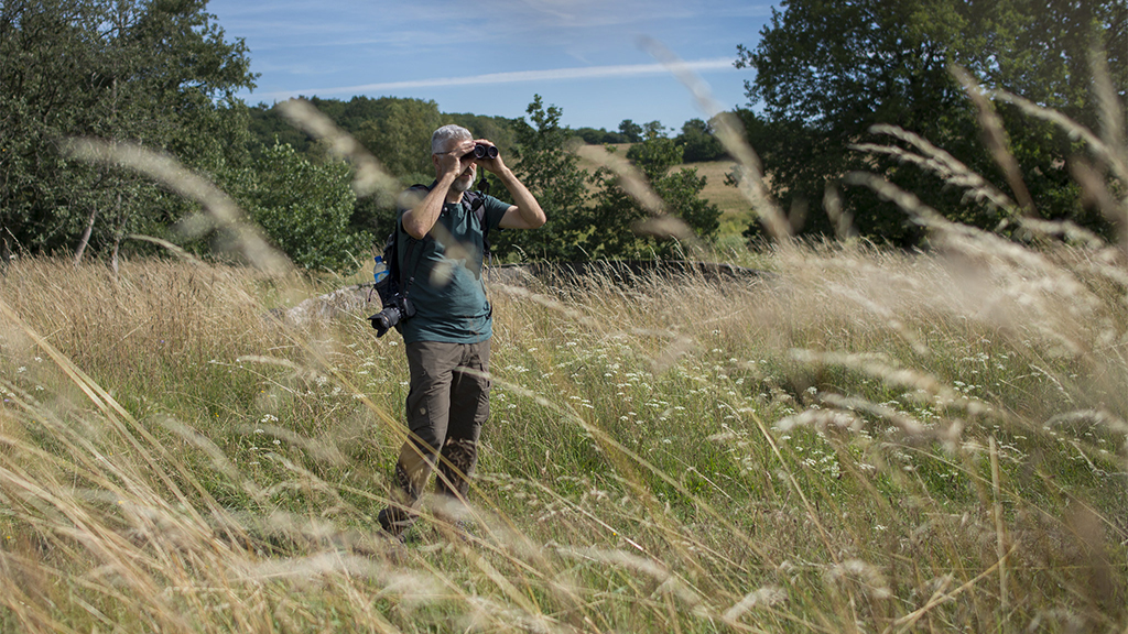 A man looks through his binoculars at Tinnet Krat