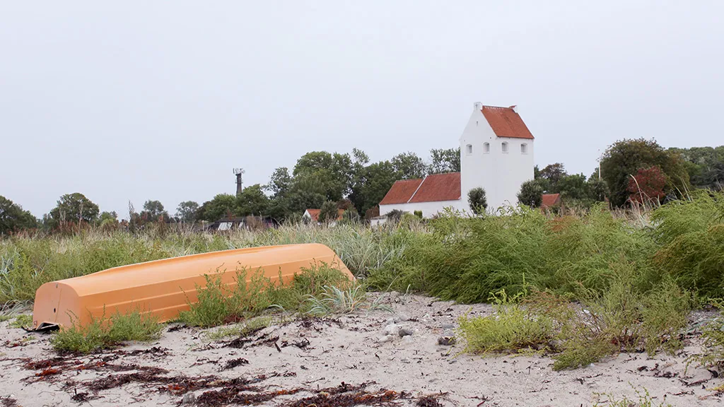 Robåd ligger på stranden med Endelave Kirke i baggrunden