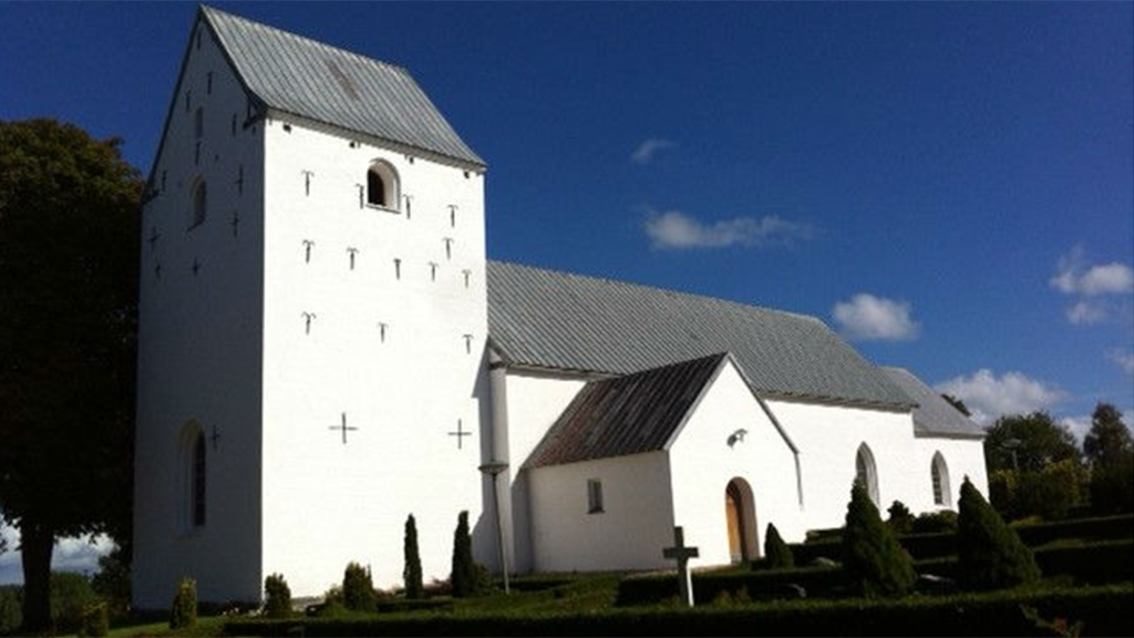 Hansted Kirke set fra kirkegården på en solskinsdag