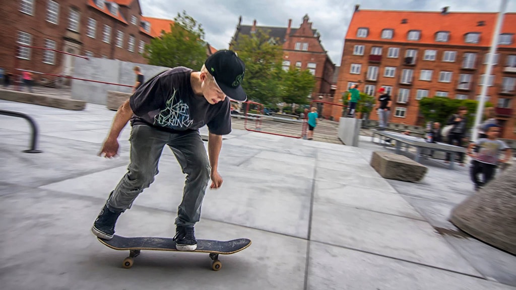 Dreng står på skateboard på skatebanen ved Rådhusparken
