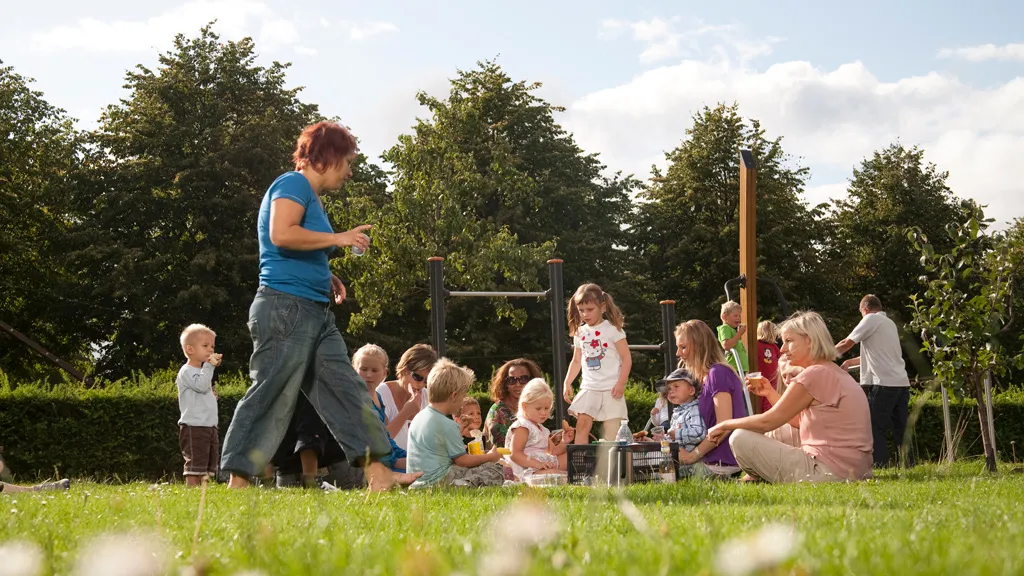 Mange kvinder og børn holder picnic på græsset i Bygholm Park i Horsens