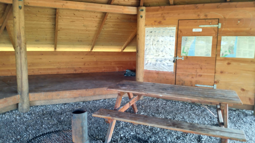 Shelter, table, and information boards in the grill hut at Hølken Beach