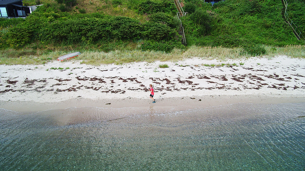Rude Beach seen from the air with a runner along the water's edge