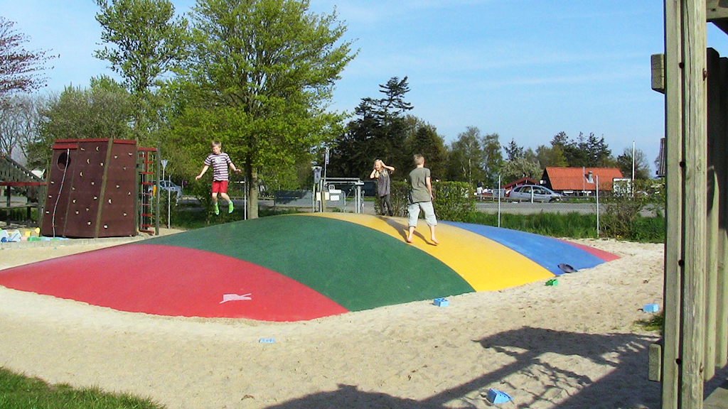 Playing children on a jumping pillow at Saksild Beach Camping