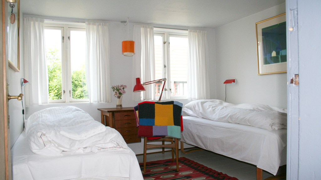 Room with two made-up beds and a colorful patchwork rug at Louises Pensionat on Endelave