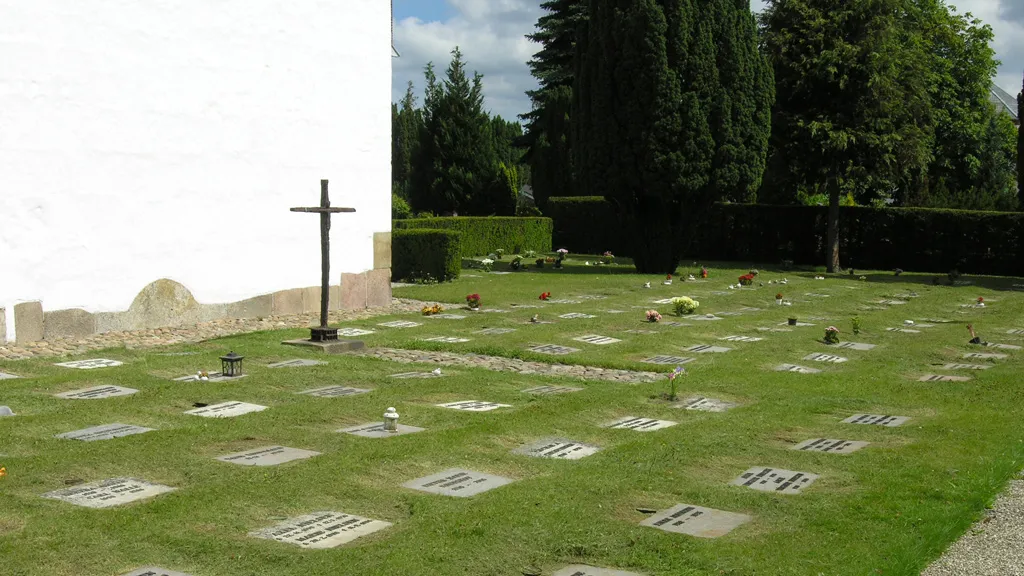 Gravsteder i græsset ved Odder Sognekirke